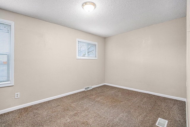 spare room with visible vents, baseboards, carpet, and a textured ceiling