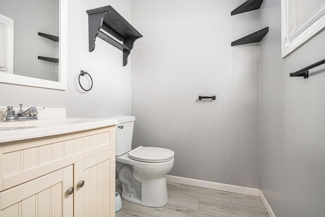 bathroom with toilet, vanity, and baseboards