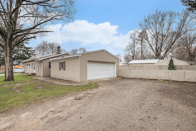 garage with fence and dirt driveway