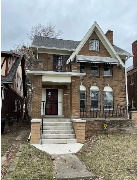view of front of house featuring brick siding, a balcony, and a chimney