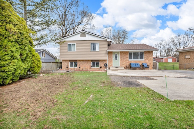 back of property with brick siding, a yard, a shed, and fence