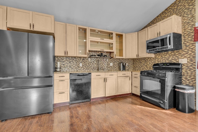 kitchen with black appliances, light brown cabinetry, backsplash, vaulted ceiling, and light stone counters