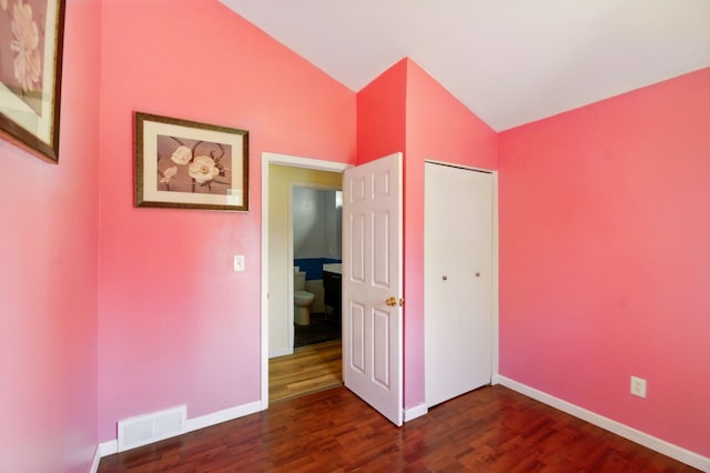 unfurnished bedroom featuring a closet, dark wood-style flooring, baseboards, visible vents, and high vaulted ceiling