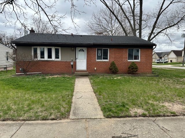 view of front of house with brick siding, a front lawn, and a chimney
