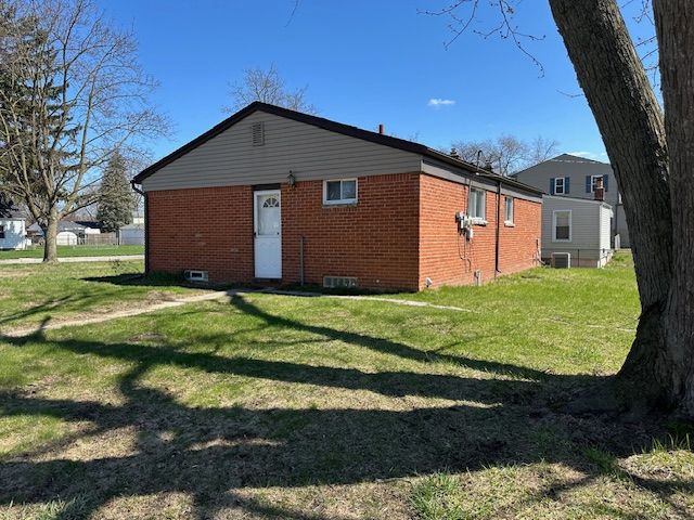 rear view of property featuring brick siding and a lawn