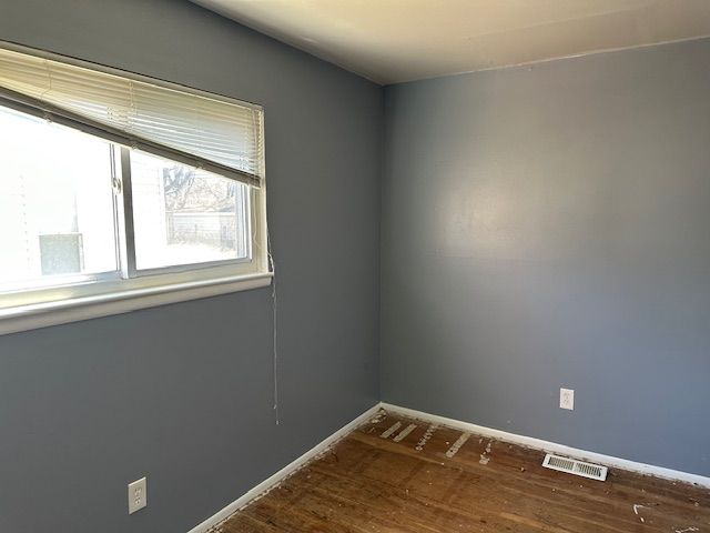 spare room featuring dark wood-style flooring, baseboards, and visible vents