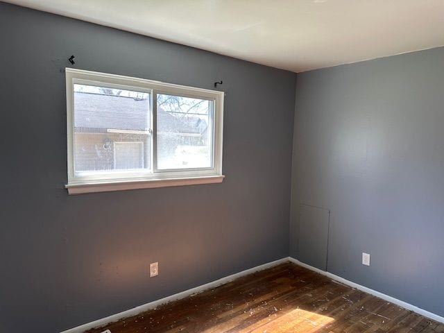 unfurnished room with dark wood-type flooring and baseboards