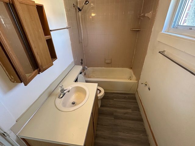 full bath with toilet, vanity, shower / washtub combination, and wood finished floors