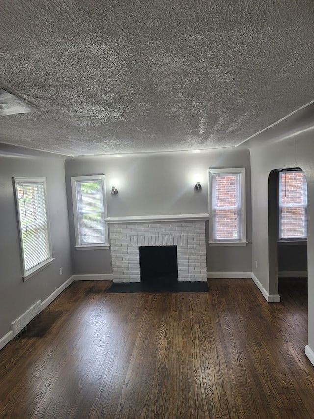 18639 Appoline St, Detroit, MI 48235 - unfurnished living room with a fireplace, a textured ceiling, baseboards, wood finished floors, and arched walkways
