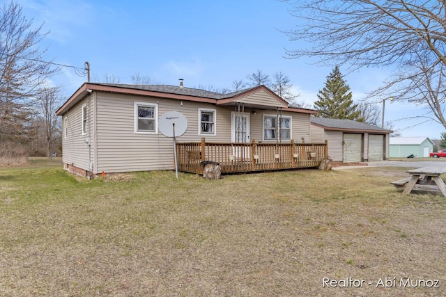 view of front of property with a front yard, a deck, and a detached garage