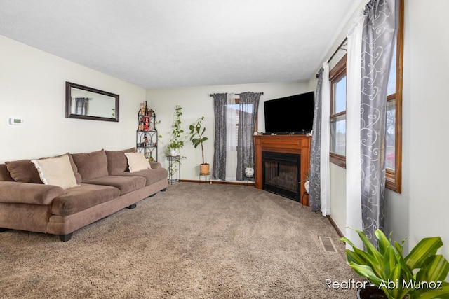carpeted living area featuring visible vents, baseboards, and a fireplace