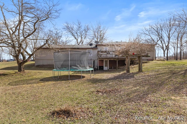 back of property with a yard, a trampoline, and a deck