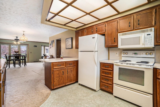 kitchen featuring white appliances, brown cabinets, light countertops, and a peninsula
