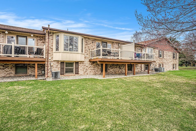 rear view of property with brick siding, central air condition unit, a wooden deck, and a lawn