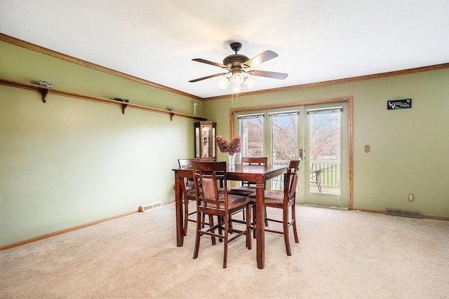dining space featuring light colored carpet, baseboards, a ceiling fan, and visible vents