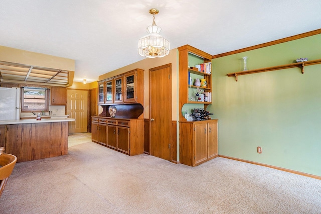 kitchen featuring light carpet, an inviting chandelier, brown cabinets, and freestanding refrigerator