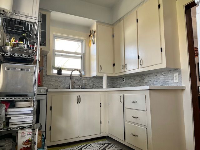 kitchen featuring light countertops, backsplash, and white cabinetry