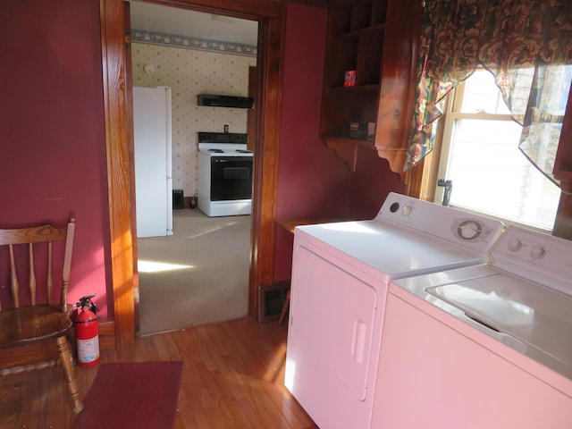 clothes washing area featuring independent washer and dryer, laundry area, and light wood-style flooring