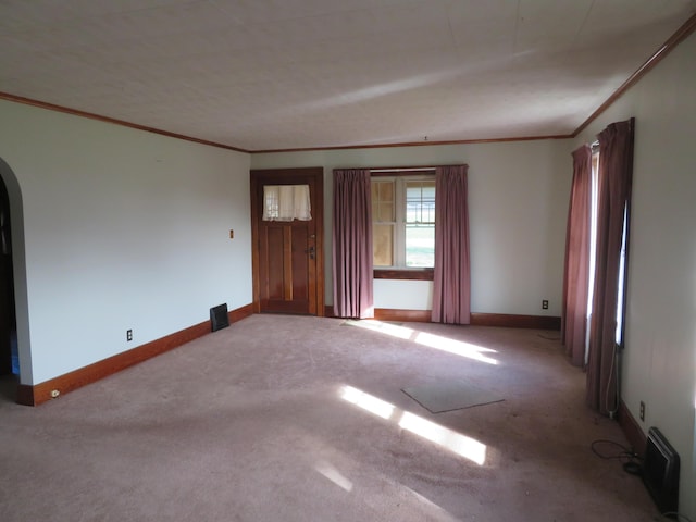 carpeted spare room featuring arched walkways, baseboards, and ornamental molding
