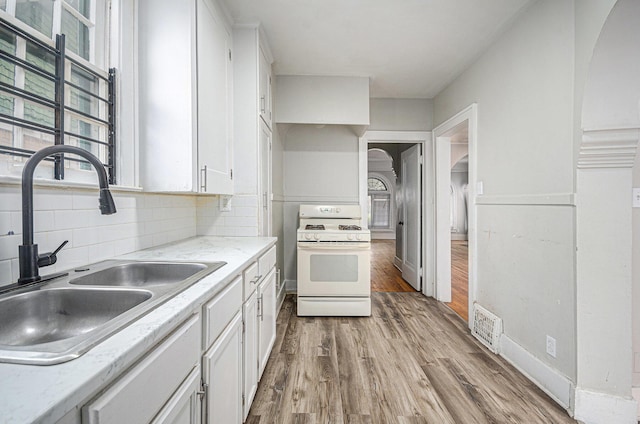 13605 Griggs St, Detroit, MI 48238 - kitchen featuring white cabinets, arched walkways, a sink, white range with gas stovetop, and light wood finished floors