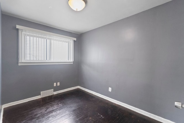 empty room featuring visible vents, baseboards, and wood finished floors
