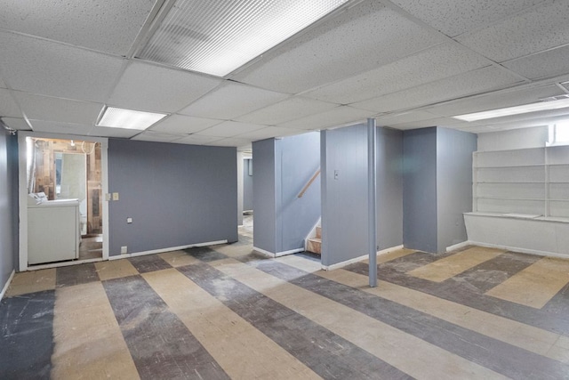 finished below grade area with a paneled ceiling, washer / clothes dryer, stairway, wood finished floors, and baseboards