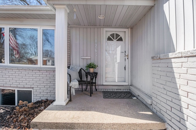 view of exterior entry with board and batten siding and brick siding