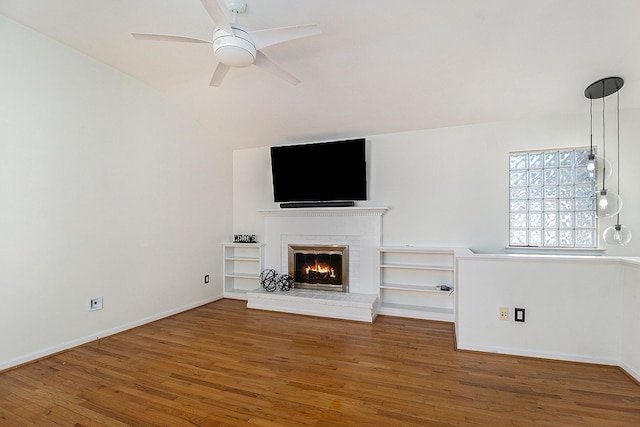 unfurnished living room with baseboards, vaulted ceiling, a fireplace, a ceiling fan, and wood finished floors