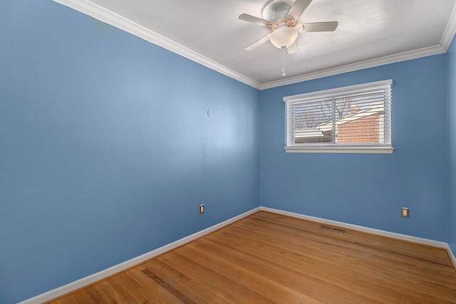 spare room with crown molding, ceiling fan, visible vents, wood finished floors, and baseboards