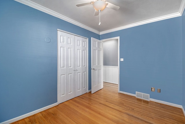 unfurnished bedroom featuring crown molding, light wood finished floors, baseboards, and visible vents