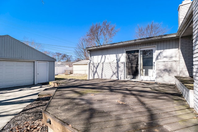 wooden deck with an outbuilding, driveway, a detached garage, and fence