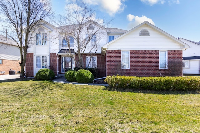 traditional-style home with a front yard, brick siding, and central air condition unit