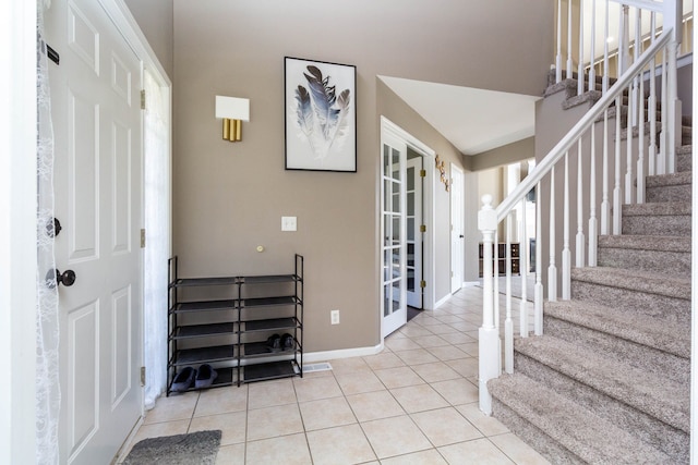 foyer featuring stairs, light tile patterned flooring, and baseboards