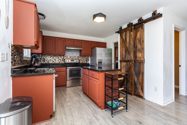 kitchen with stainless steel appliances, a sink, light wood-style flooring, and a barn door