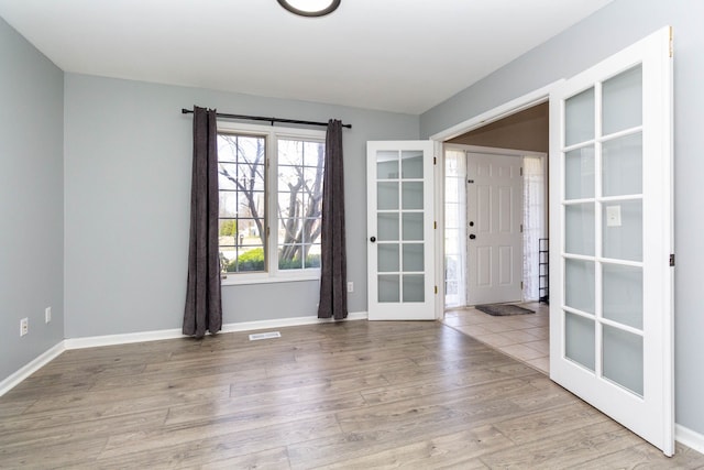 empty room featuring french doors, baseboards, and wood finished floors