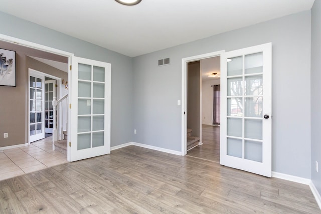 unfurnished room with french doors, stairway, wood finished floors, and baseboards