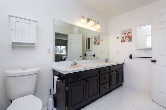 bathroom featuring toilet, double vanity, tile patterned floors, and baseboards