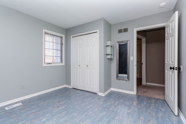 unfurnished bedroom with wood finished floors, baseboards, and a closet