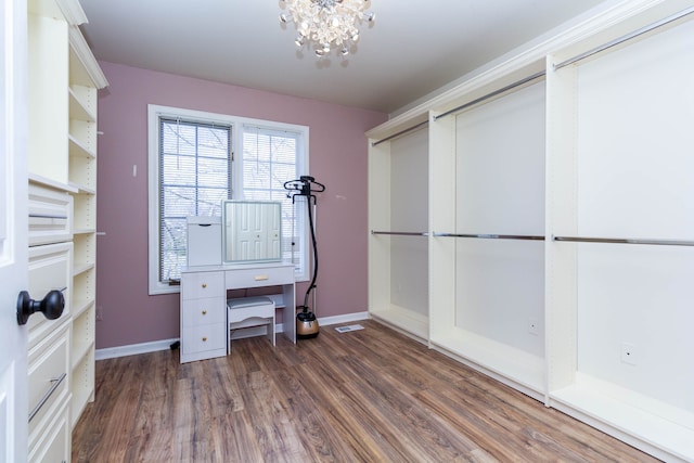 walk in closet with wood finished floors and a chandelier