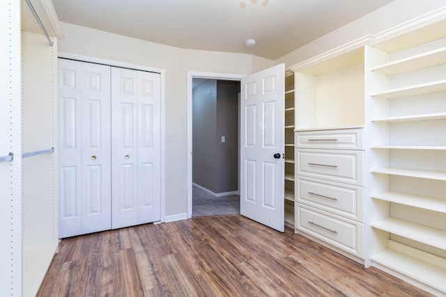 unfurnished bedroom featuring wood finished floors, a closet, and baseboards