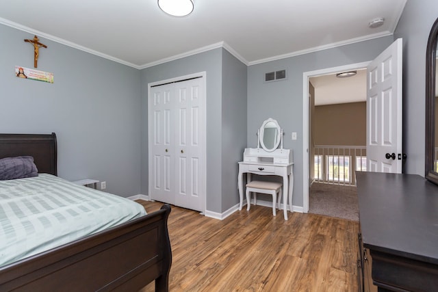 bedroom featuring wood finished floors, baseboards, a closet, and ornamental molding