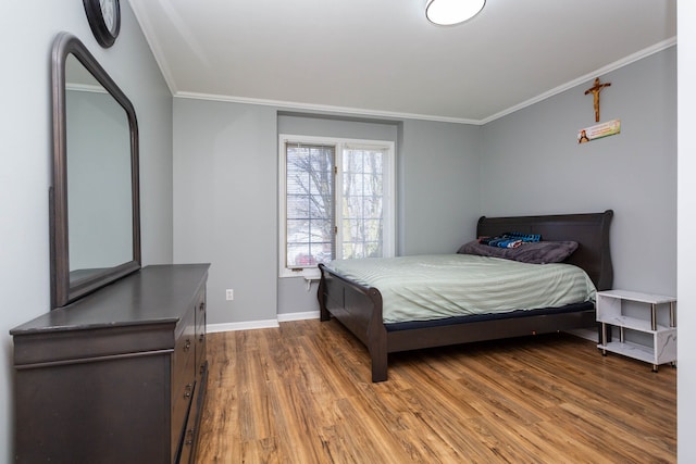 bedroom featuring wood finished floors, crown molding, and baseboards