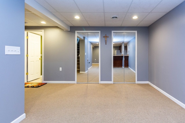 unfurnished bedroom with multiple closets, light carpet, recessed lighting, a paneled ceiling, and baseboards
