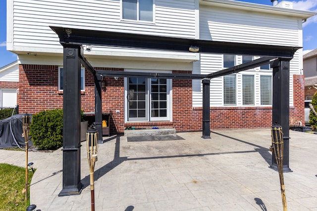 back of property with brick siding and a patio