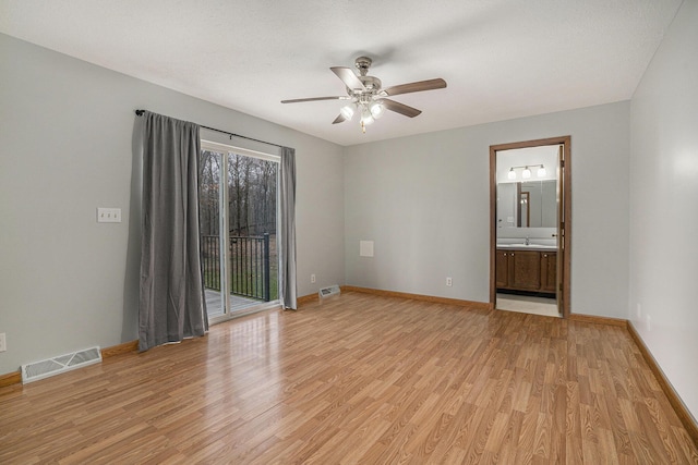 spare room featuring light wood-style floors, ceiling fan, visible vents, a sink, and baseboards