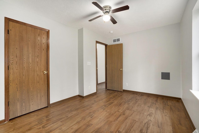 unfurnished bedroom featuring visible vents, baseboards, and wood finished floors