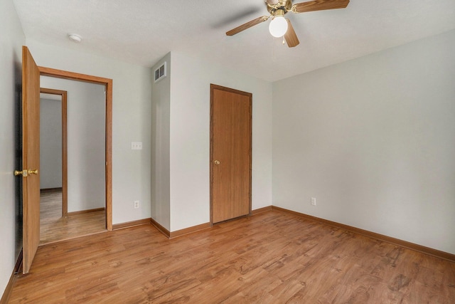 unfurnished bedroom featuring a closet, baseboards, light wood-style flooring, a ceiling fan, and visible vents