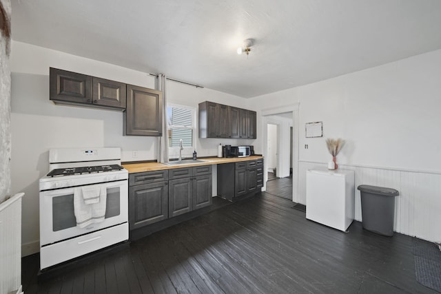 kitchen with refrigerator, dark wood-style floors, wooden counters, white range with gas stovetop, and a sink