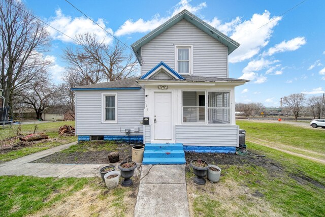 view of front of home featuring roof with shingles, a front yard, and entry steps
