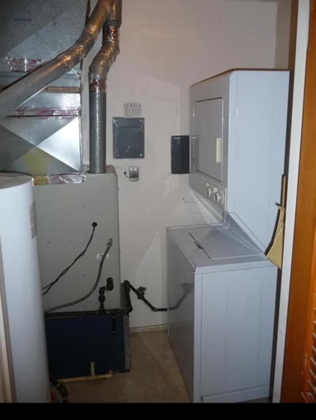 laundry area with stacked washer and clothes dryer, gas water heater, and laundry area